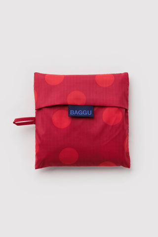 Folding red polka-dot BAGGU bag with foldover flap and small loop strap