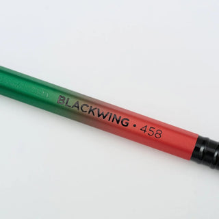 A close-up of a pencil with a green-to-red gradient finish and text reading 'BLACKWING 458'.