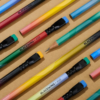 Colorful Blackwing pencils arranged on a brown surface