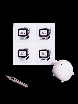Sheet of stickers with vintage computer design, a white ghost figurine, and a fountain pen nib on a black background.