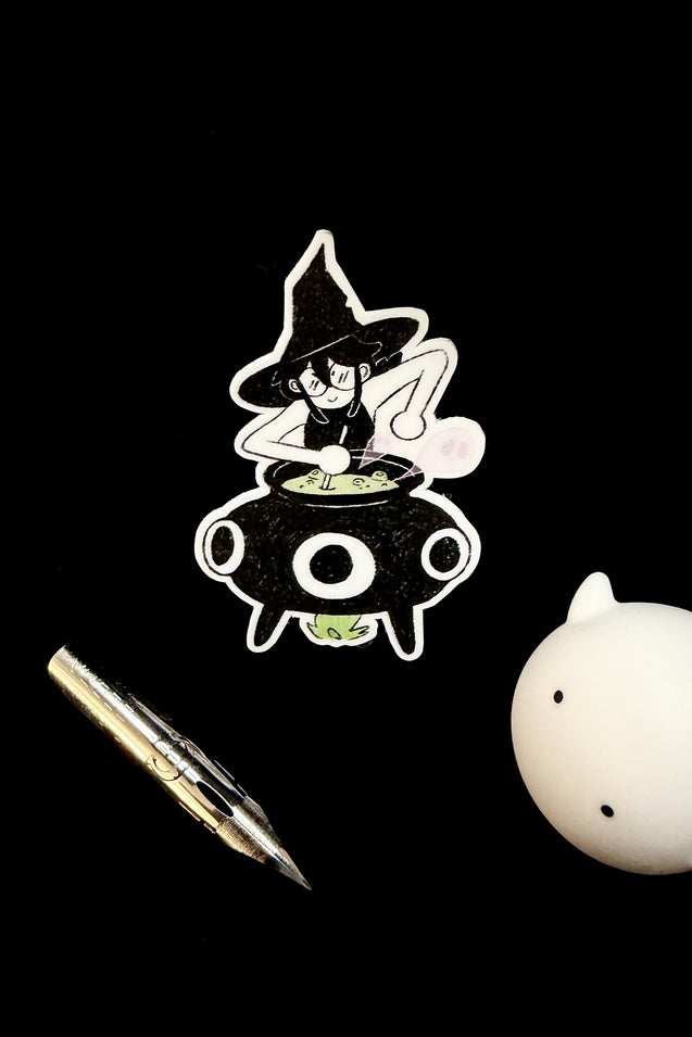 Vinyl witch-and-cauldron sticker, cartoon spellcaster in black hat with white outline