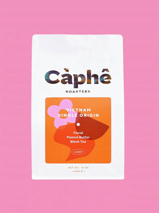 A white bag of Câphé Roasters Vietnam Single Origin displayed against a solid pink background.
