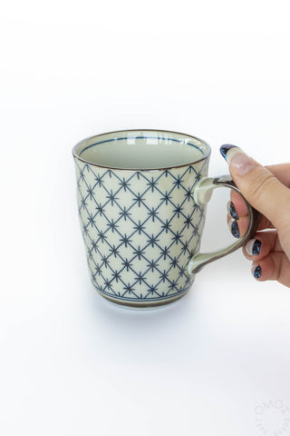 Celadon lattice 8 oz mug with star lattice pattern, held by hand at handle