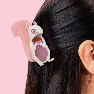 Hair clip shaped like a squirrel in someone's hair against a pink background