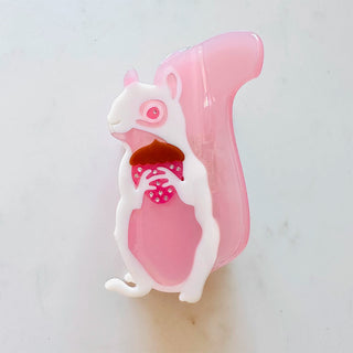 Pink squirrel-shaped hair clip holding an acorn