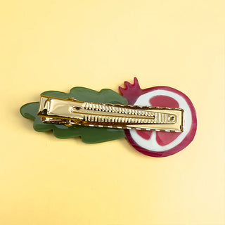 Backside of pomegranate-shaped hair clip with a green leaf. Shows teeth of hair clip