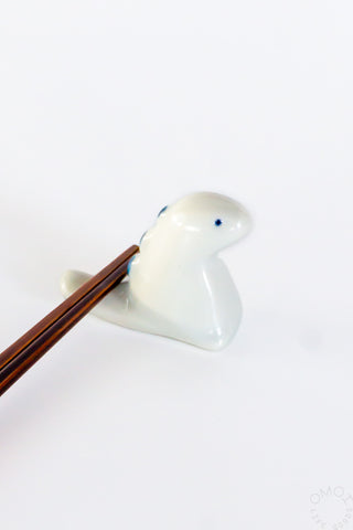 White ceramic tyrannosaurus chopstick rest with wooden chopsticks