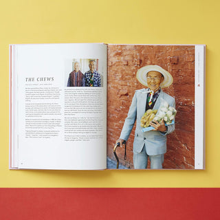 Open book showing a portrait of a man with a hat and flowers against a brick wall.