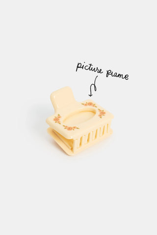 Yellow hair clip with picture frame feature on a white background
