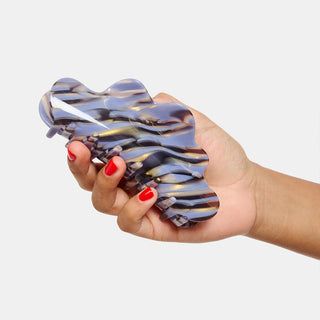 Blue and amber marble claw clip held in hand, glossy ridged grip