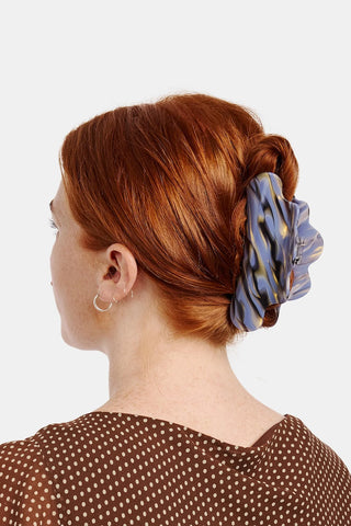 Blue and amber marble claw clip holding brown low bun