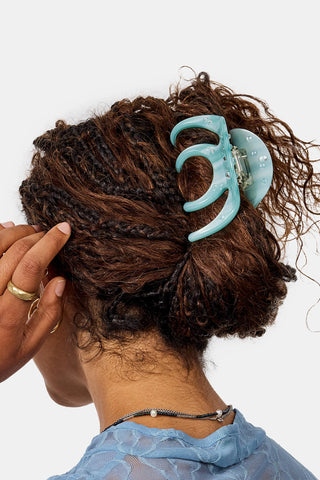 Octopus claw hair clip on dark curly hair, light blue translucent shell design.