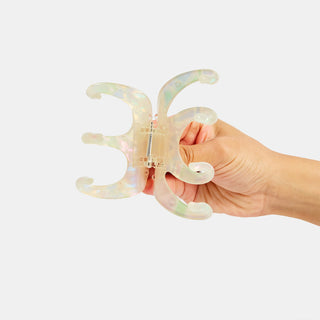 Iridescent octopus claw hair clip held in hand, pearl shimmer finish