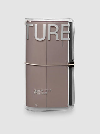 A clear notebook cover featuring large silver 'TURE' lettering and a thin horizontal metallic band around the middle on a light gray background.