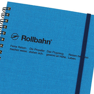 Blue spiral notebook cover with Rollbahn logo, black elastic band, and textured surface