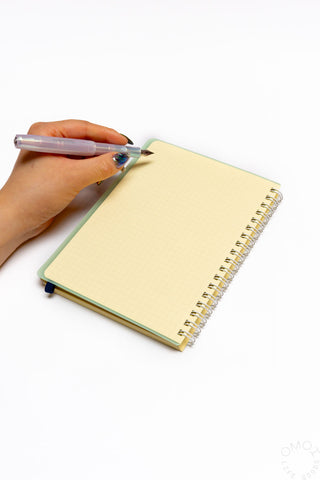 Mint spiral notebook with pen on cover, held by hand