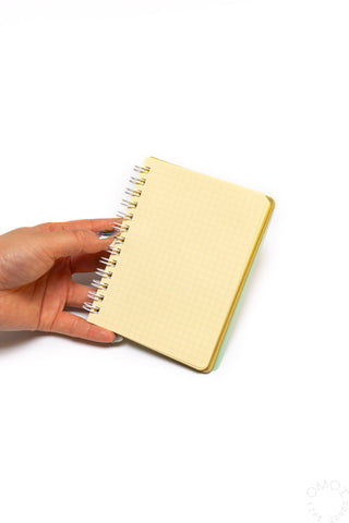 Yellow spiral notebook with rounded corners, held by hand