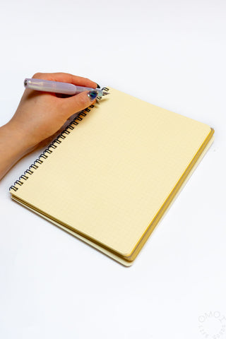 Cream spiral notebook with hand holding a pen on the open cover