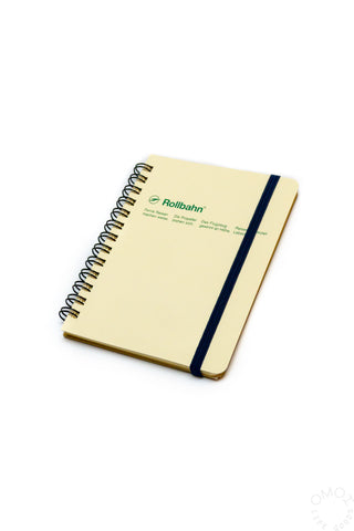 Cream spiral notebook with dark blue elastic band and green Rollbahn text