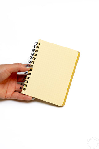 Cream spiral notebook close-up with hand near metal spiral binding