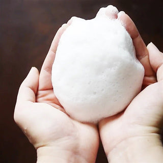 Foamy lather from facial foaming net held in hands