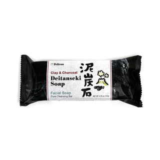 Clay & charcoal facial cleansing bar soap with front label on black wrap