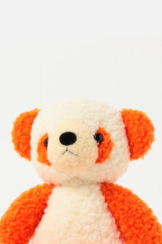 Small stuffed panda with orange accents on a white background