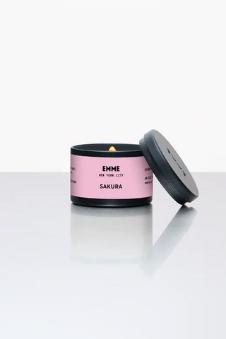 Pink cherry blossom scented candle with a black lid on a white surface