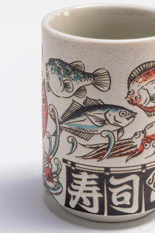 Fish teacup close-up, cream ceramic with blue fish and red koi-style illustration