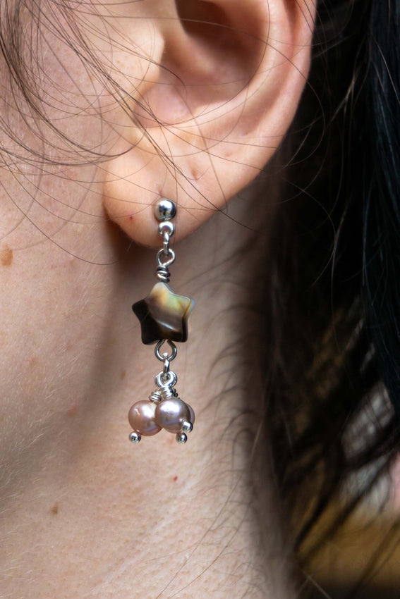 Close up of person wearing star pearl earring