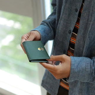Person holding a green wallet with a blurred background