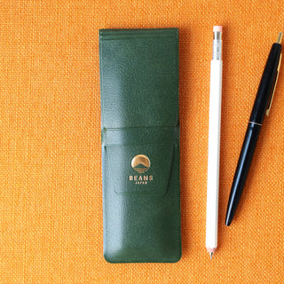 Green pencil case with BEAMS Japan logo on an orange background, accompanied by a white pencil and black pen.