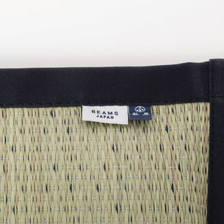 Close-up of a woven mat with a 'Beams Japan' label on a white background