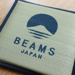 Navy cushion with 'Beams Japan' logo on a wooden surface
