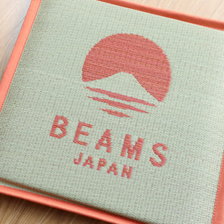 Orange and tan beams japan branded cushion on a wooden floor