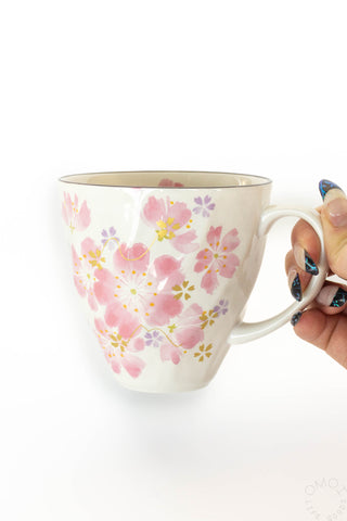 Mug with floral design held by a hand on a white background