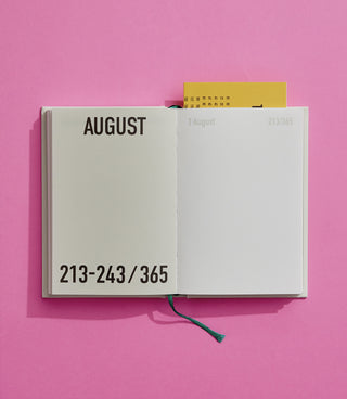 Open notebook showing August page on a pink background