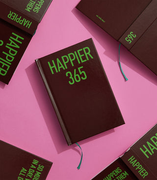 Brown book titled 'Happier 365' with green text on a pink background