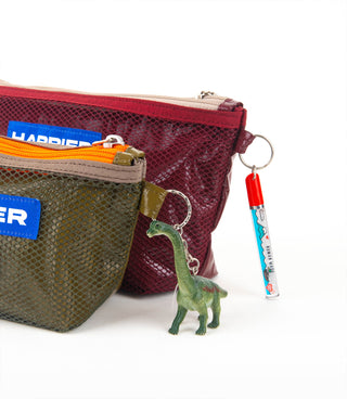Two pouches, one red and one green, with a dinosaur keychain and a marker on a white background.