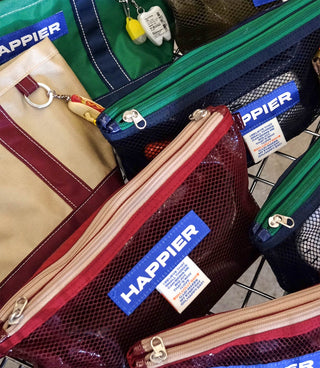 Collection of bags with 'Happier' branding on a metal surface.