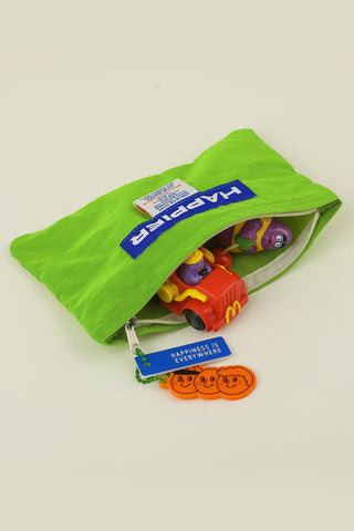 Green pouch with colorful toys and visible branding on a light beige background