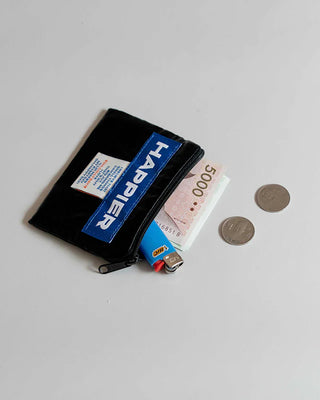 Black pouch with blue label, money, and coins on a light gray background