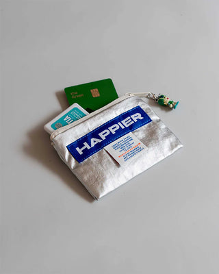 Small pouch with 'HAPPIER' branding and items coming out on a gray background