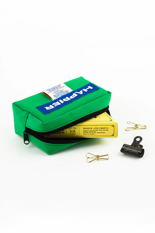 Green box with a blue label, yellow box, and small black and gold items on a white background