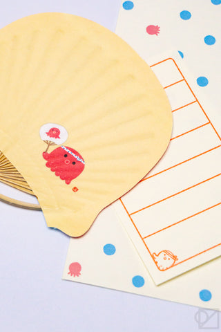 Yellow fan shaped card with a red octupus character with colorful stationery