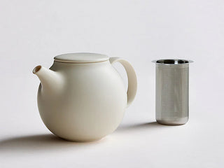 White teapot with a strainer next to it