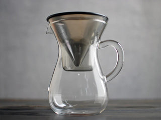 A clear glass pour-over coffee carafe with a filter shown against a gray background.