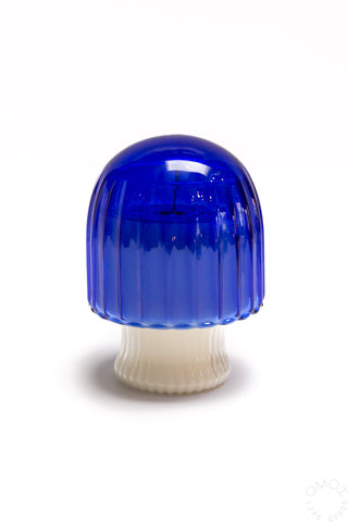 Blue and white mushroom-shaped glass candle on a white background