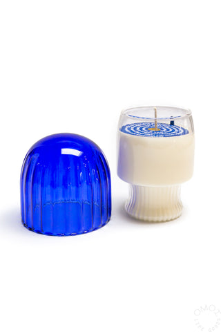 Glass candle with lid next to it on a white background