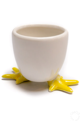 Close up of white ceramic egg soap cup with yellow feet on a white background